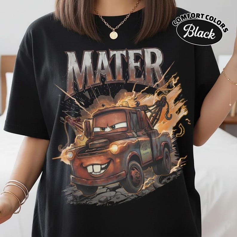 May include: Black t-shirt with a cartoon image of Mater from the film Cars. The word "MATER" is printed above the image in a metallic font. The shirt has the words "COMFORT COLORS Black" printed on the upper right.