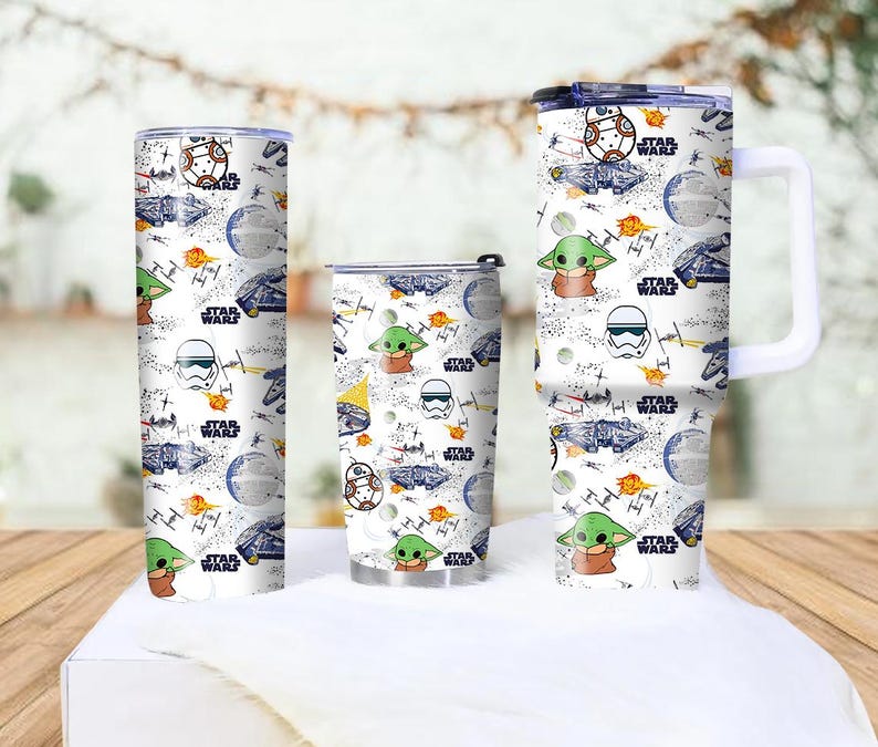 Op de afbeelding: Drie witte Star Wars-thema bekers met verschillende ontwerpen. De ontwerpen omvatten personages als Baby Yoda, BB-8 en Stormtroopers, samen met ruimteschepen en het Star Wars-logo. De bekers zijn cilindrisch en hebben een witte achtergrond.