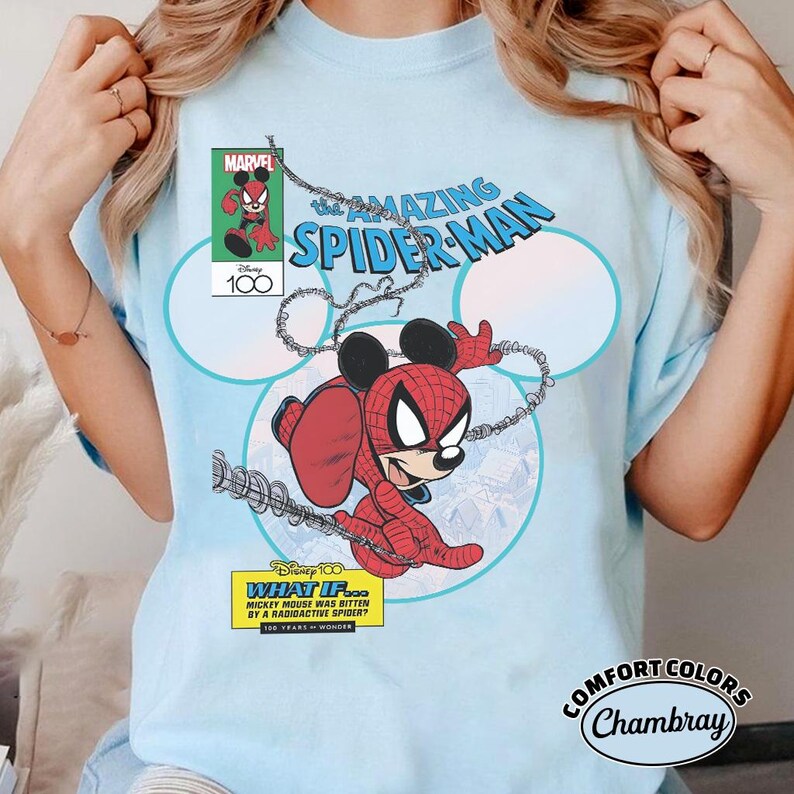 May include: Light blue t-shirt featuring a comic book-style graphic of Mickey Mouse as Spider-Man. The design includes the text "The Amazing Spider-Man," "Marvel," and "Disney 100." The shirt also has the text "What If... Mickey Mouse Was Bitten By A Radioactive Spider?"