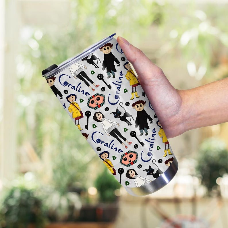 May include: A stainless steel tumbler featuring a repeating pattern of characters and the word "Coraline" in a script font. The design includes figures in yellow coats, black cats, and key illustrations on a light gray background.