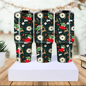 Pode incluir: Tr&ecirc;s canecas isoladas com um design festivo de Natal. As canecas apresentam um fundo verde escuro com ilustra&ccedil;&otilde;es de Baby Yoda com um chap&eacute;u de Papai Noel, renas, flocos de neve e caixas de presente. As canecas t&ecirc;m aproximadamente 25 cm de altura.