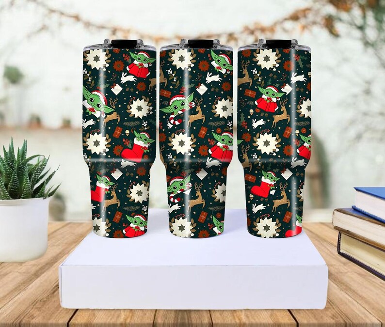 Pode incluir: Tr&ecirc;s canecas isoladas com um design festivo de Natal. As canecas apresentam um fundo verde escuro com ilustra&ccedil;&otilde;es de Baby Yoda com um chap&eacute;u de Papai Noel, renas, flocos de neve e caixas de presente. As canecas t&ecirc;m aproximadamente 25 cm de altura.