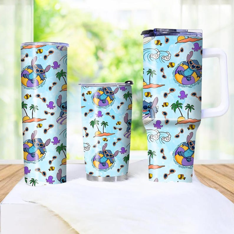 May include: Three stainless steel tumblers with a light blue background featuring a cartoon character in a floatie, sunglasses, palm trees, and sea creatures. The tumblers are different sizes, with one having a handle.