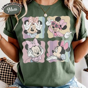 May include: Green Comfort Colors t-shirt featuring four panels with Minnie Mouse illustrations. Each panel showcases a different pose of Minnie Mouse in various outfits and expressions. The shirt has the text "Comfort Colors" and "Moss" in a circular design.