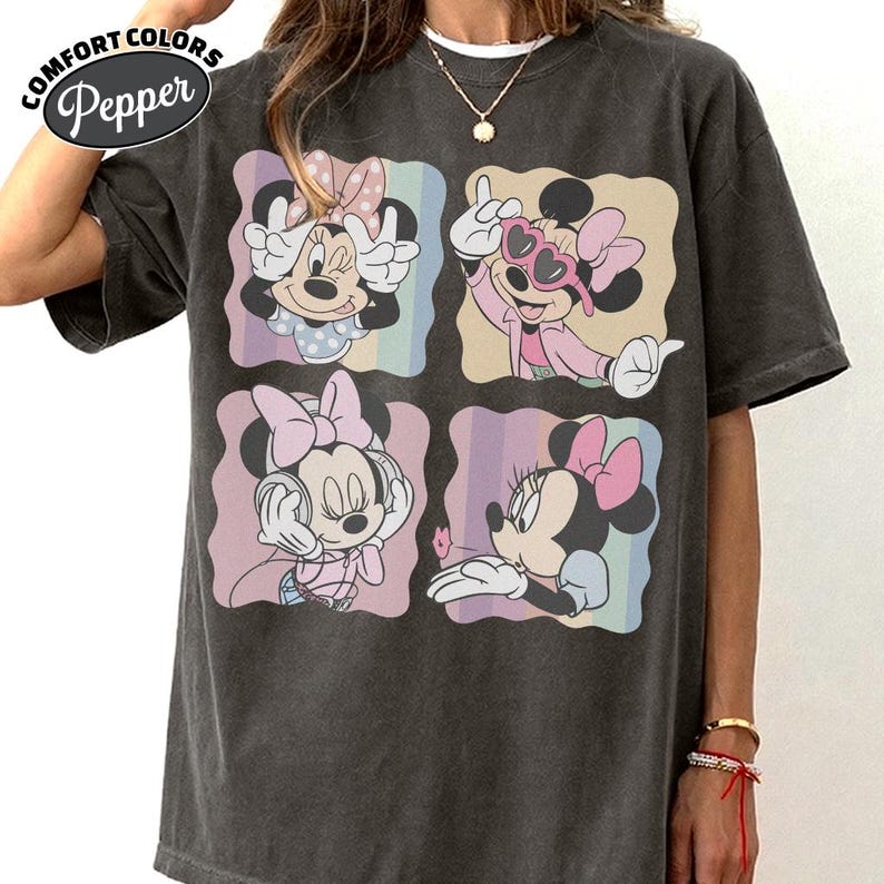 May include: Dark grey Comfort Colors t-shirt featuring four panels with Minnie Mouse illustrations. Each panel showcases Minnie in different poses, with pastel rainbow backgrounds. The shirt has a relaxed fit and the Comfort Colors logo is visible.