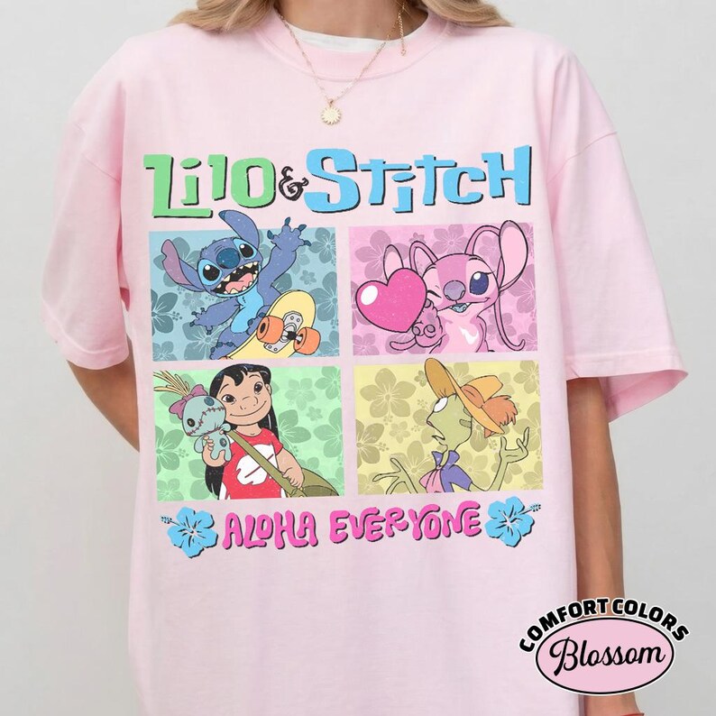 May include: Pale pink t-shirt with a colourful graphic of Lilo & Stitch characters. The design includes the words "Lilo & Stitch" and "Aloha Everyone". The shirt is a Comfort Colors Blossom tee.