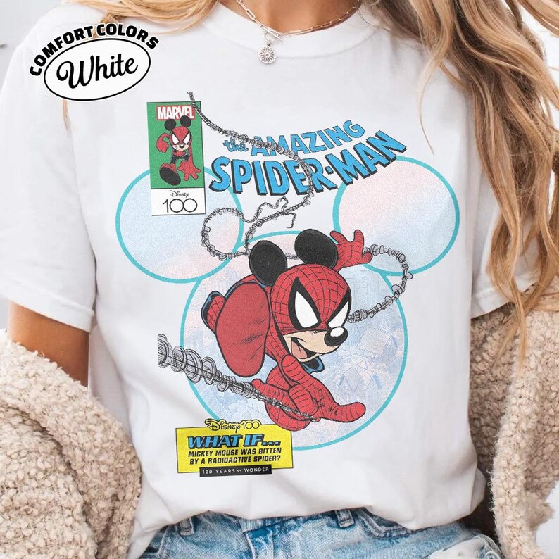 May include: White t-shirt featuring a comic-style illustration of Mickey Mouse as Spider-Man. The design includes the text "The Amazing Spider-Man" and "What If... Mickey Mouse was bitten by a radioactive spider?" with the Marvel and Disney 100 logos.