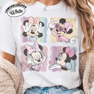 May include: White Comfort Colors t-shirt featuring four panels with Minnie Mouse illustrations. Each panel showcases Minnie in different poses, with a pink bow, against a pastel rainbow background. The shirt has the text "Comfort Colors White" in a circular design.