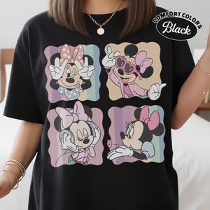 May include: Black t-shirt featuring a four-panel design of Minnie Mouse in various poses. Each panel has a pastel rainbow background. The shirt has the words "Comfort Colors Black" printed on the upper right.