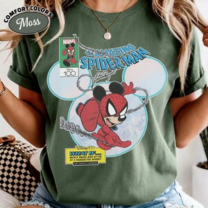 May include: Moss green Comfort Colors t-shirt featuring a Marvel comic-style graphic of Mickey Mouse as Spider-Man. The design includes the text "The Amazing Spider-Man" and "What If... Mickey Mouse was bitten by a radioactive spider?"