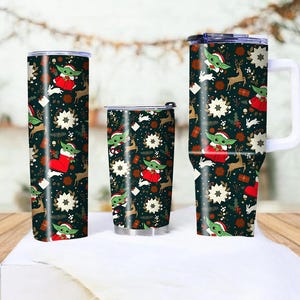 Pode incluir: Tr&ecirc;s canecas isoladas com um design festivo de Natal. As canecas apresentam um fundo verde escuro com um padr&atilde;o de Baby Yoda com roupa de Papai Noel, renas, flocos de neve e presentes. Uma caneca tem uma al&ccedil;a.
