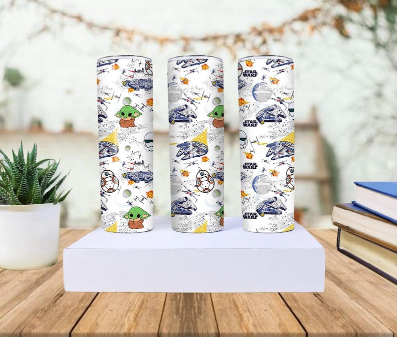 Op de afbeelding: Drie witte Star Wars-tumblers met een herhalend patroon van personages en schepen. Het ontwerp bevat Baby Yoda, BB-8 en de Millennium Falcon. De tumblers zijn cilindrisch en staan rechtop op een wit oppervlak.