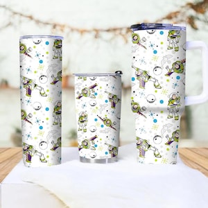 May include: Three white tumblers with a repeating pattern of a cartoon space ranger, planets, and stars. The tumblers are different sizes, with one having a handle. The design includes green, purple, blue, and black accents.