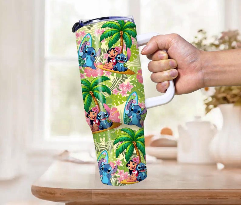May include: A large, insulated tumbler featuring a colorful tropical design with palm trees, flowers, and cartoon characters. The tumbler has a white handle and a clear lid. The design includes images of Stitch and Lilo.
