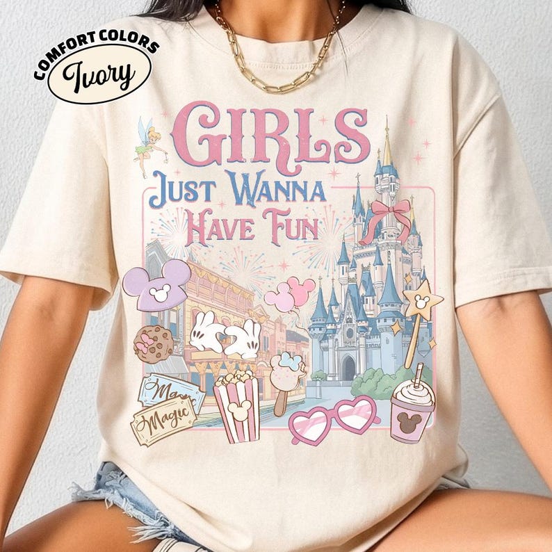 May include: Ivory Comfort Colors t-shirt with a graphic that says "GIRLS JUST WANNA HAVE FUN". The graphic includes a castle, fireworks, and cartoon images of Mickey Mouse, popcorn, and ice cream.