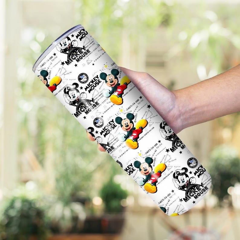 May include: A white tumbler featuring a repeating pattern of Mickey Mouse illustrations in various poses. The design includes the text "MICKEY MOUSE" and other graphic elements. The tumbler is held in a hand.