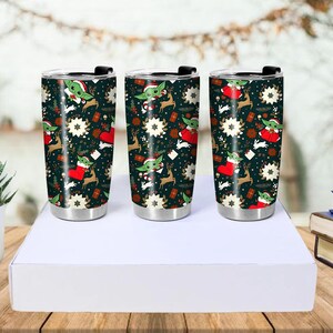 Pode incluir: Tr&ecirc;s canecas de viagem de a&ccedil;o inoxid&aacute;vel com tampas pretas. As canecas apresentam um fundo verde escuro com um padr&atilde;o repetido de um personagem alien&iacute;gena verde com um chap&eacute;u de Papai Noel, renas, estrelas e meias vermelhas. As canecas s&atilde;o exibidas em uma caixa branca.