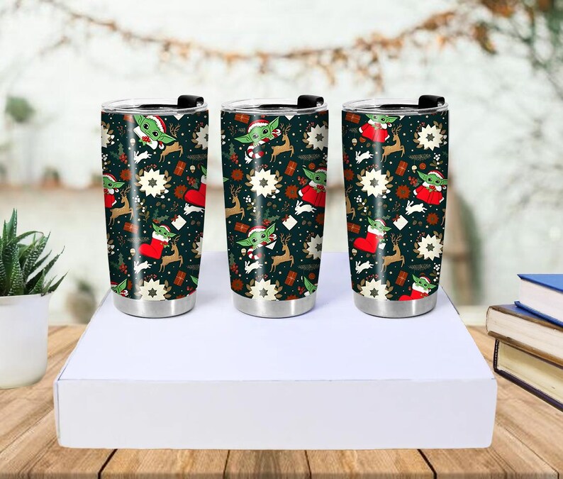 Pode incluir: Tr&ecirc;s canecas de viagem de a&ccedil;o inoxid&aacute;vel com tampas pretas. As canecas apresentam um fundo verde escuro com um padr&atilde;o repetido de um personagem alien&iacute;gena verde com um chap&eacute;u de Papai Noel, renas, estrelas e meias vermelhas. As canecas s&atilde;o exibidas em uma caixa branca.