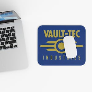 May include: A blue rectangular mousepad with the text "VAULT-TEC INDUSTRIES" in gold. A white computer mouse is on the mousepad. A laptop is partially visible in the image.