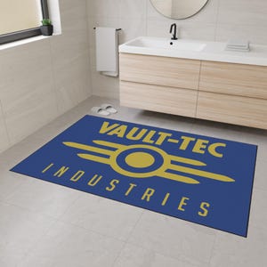 Può includere: Un tappeto rettangolare blu con le parole "VAULT-TEC INDUSTRIES" in giallo. Il tappeto presenta il logo Vault-Tec, un cerchio giallo all'interno di un simbolo atomico giallo stilizzato. Il tappeto è posizionato su un pavimento piastrellato in un bagno.