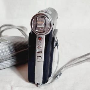 May include: A set of three ceramic mugs with a speckled, matte finish. The mugs are in shades of cream, light gray, and dark gray. Each mug has a simple, minimalist design and a rounded handle.