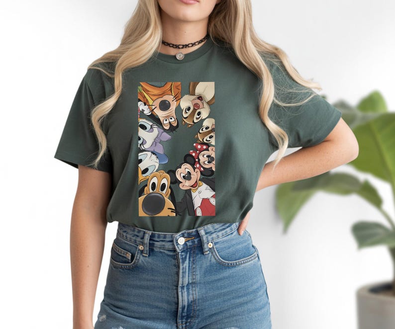 May include: Dark green t-shirt featuring a graphic of Disney characters, including Mickey Mouse, Minnie Mouse, and Pluto. The characters are arranged in a semi-circle. The shirt is made of a soft material.
