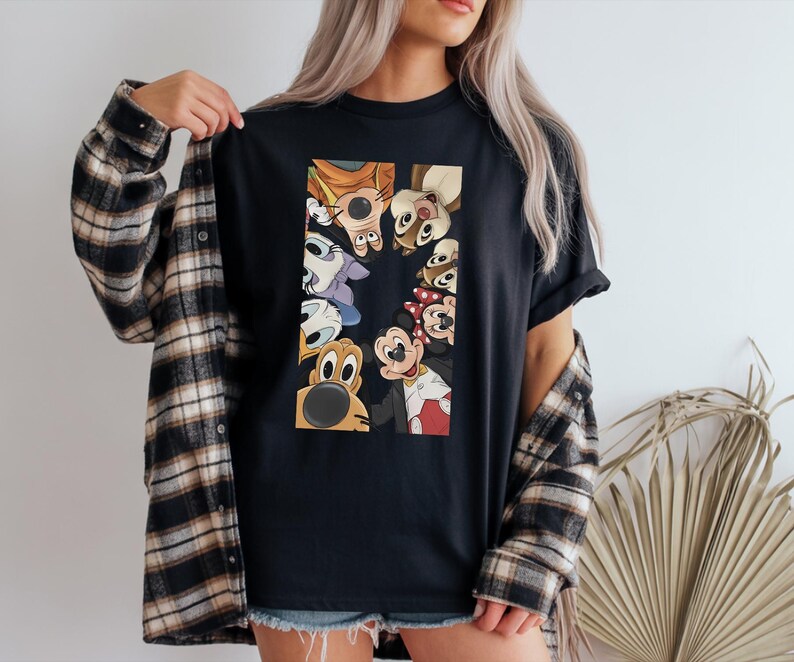 May include: Black t-shirt featuring a rectangular graphic of cartoon characters including Mickey Mouse, Donald Duck, and Goofy. The characters are arranged in a vertical pattern. The shirt is worn with a plaid button-down shirt.
