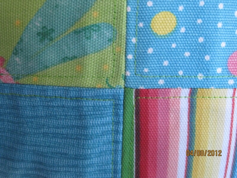 May include: Close-up of a patchwork fabric with a variety of patterns. The design includes sections of teal, green, and blue fabric with polka dots, stripes, and floral elements. The date "04/08/2012" is visible in the bottom right corner.