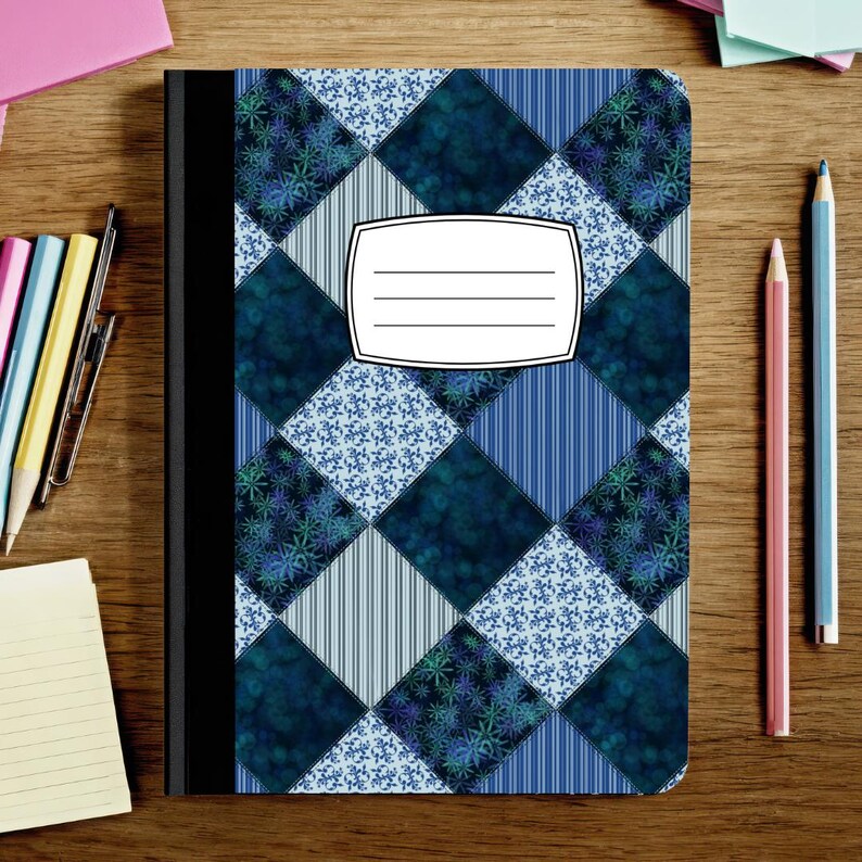 May include: A notebook with a black spine and a cover featuring a diamond-patterned quilt design in shades of blue, white, and dark teal. The pattern alternates between floral prints and vertical stripes. A white label with three lines is centered.
