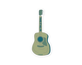 Pode incluir: Um autocolante com uma guitarra acústica estilizada em tons de verde e azul. A guitarra tem o texto "TAKE IT ALL IN" impresso verticalmente no braço. O design é simples e moderno, com uma borda branca.