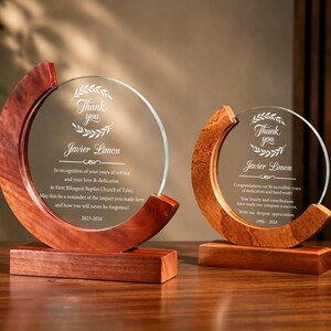 May include: Two circular glass plaques set in crescent-shaped wooden frames on rectangular wooden bases. The glass features engraved text including 'Thank you', 'Javier Limon', and commemorative messages for years of service from 2023-2026 and 1986-2026.