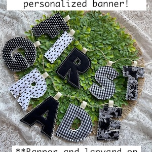 May include: A fabric banner spelling FIRST GRADE with individual stuffed letters in black and white patterns including polka dots, gingham, and floral prints. The text Match your lanyard with a personalized banner! and **Banner and lanyard on seperate listings** is visible.