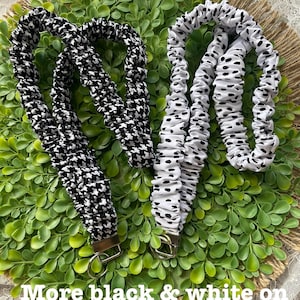 May include: Two fabric lanyards with metal hardware. One lanyard features a black and white houndstooth pattern, while the other has a white fabric with black spots. Both are gathered and ruffled along the length of the strap.