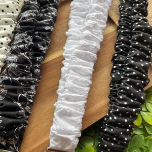 May include: Four fabric lanyards with silver-tone metal hardware and key rings. The collection includes a white lanyard with black polka dots, a black lanyard with a white floral pattern, a solid white eyelet lanyard, and a black lanyard with white dots.