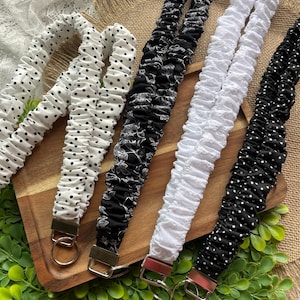 May include: Four fabric lanyards with gathered, scrunchie-style designs. One is white with black polka dots, one is black with white floral patterns, one is solid white with a textured surface, and one is black with small white polka dots.