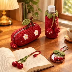 Peut inclure: Une trousse à crayons en crochet rouge avec des fleurs blanches appliquées et une tige de cerise, une housse de bouteille en crochet rouge assortie, un marque-page en crochet cerise sur un livre ouvert et un porte-clés miroir en crochet.