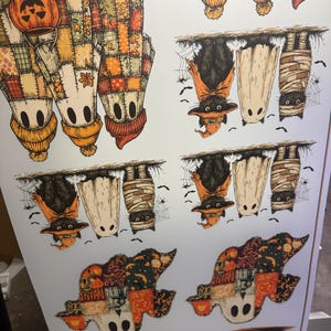 K&ouml;nnte beinhalten: Ein Bogen mit Halloween-Stickern mit verschiedenen Charakteren. Die Designs umfassen Vogelscheuchen mit K&uuml;rbissen, Flederm&auml;use mit Hexenh&uuml;ten, Geister und Mumien. Die Farbpalette wird von Orange, Braun und Creme dominiert.