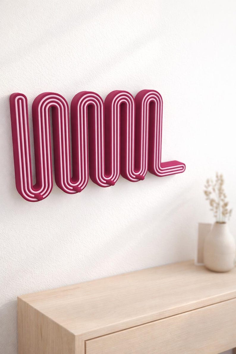 Plum Wavy key holder with light pink stripes above a pale wood console holding a vase of dried flowers