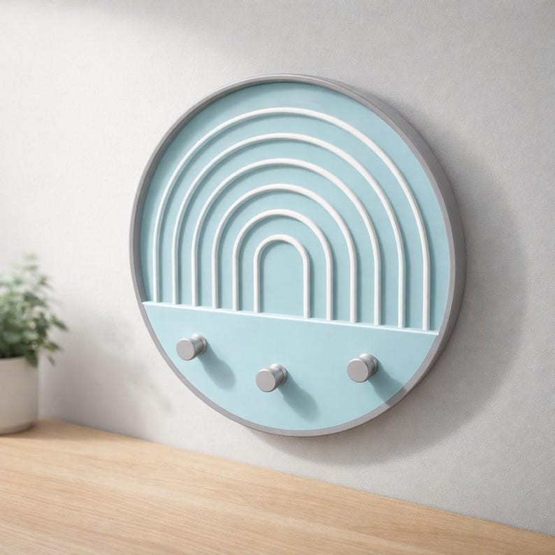 Pale blue Boho key holder up close above a wood shelf and potted plant, showing raised white arches and silver-gray pegs