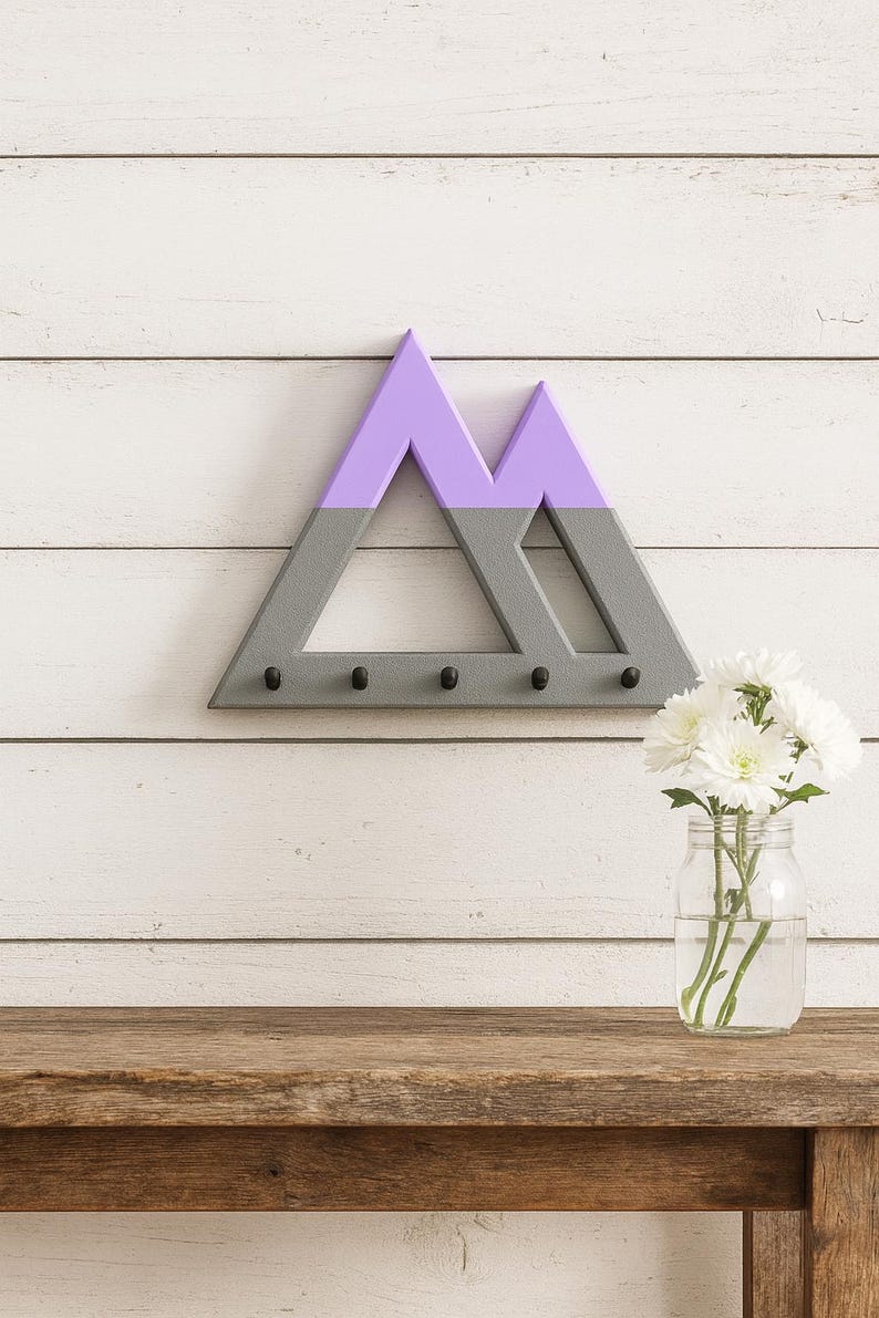 Gray and purple Mountain key holder on white shiplap above a rustic wooden table with white flowers in a glass jar