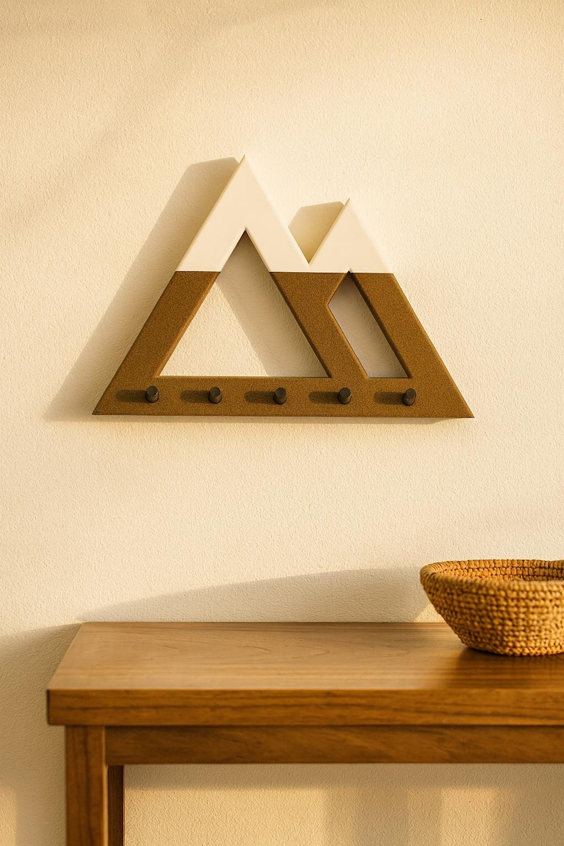 Brown and white Mountain key holder straight on in warm golden light, hung above a wood console with a woven basket