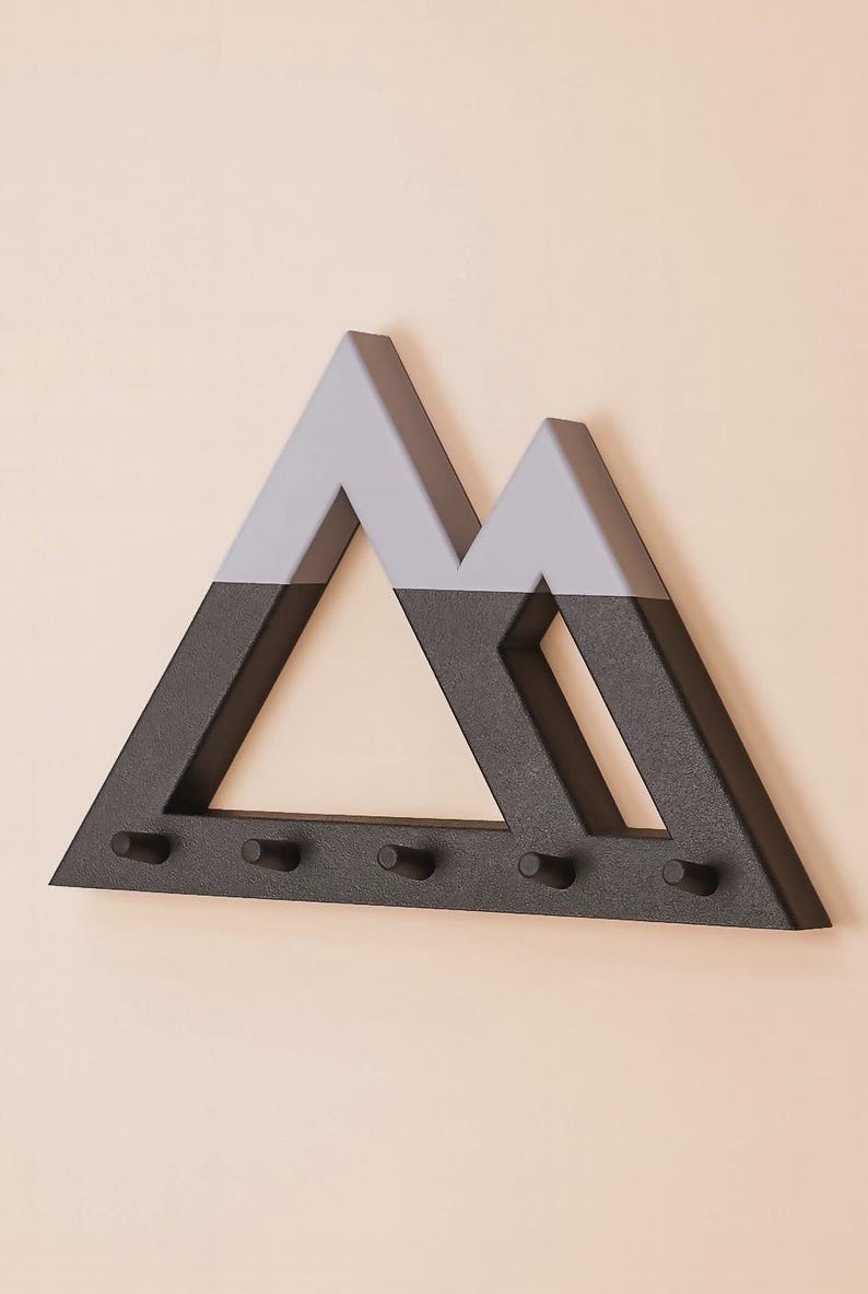 Black and gray Mountain key holder angled on a blush pink wall, showing its depth and five empty pegs
