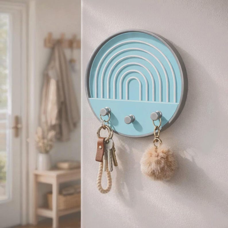 Sky blue Boho key holder in an entryway with keys on a leather and rope keychain and a fluffy pom-pom charm, a coat behind