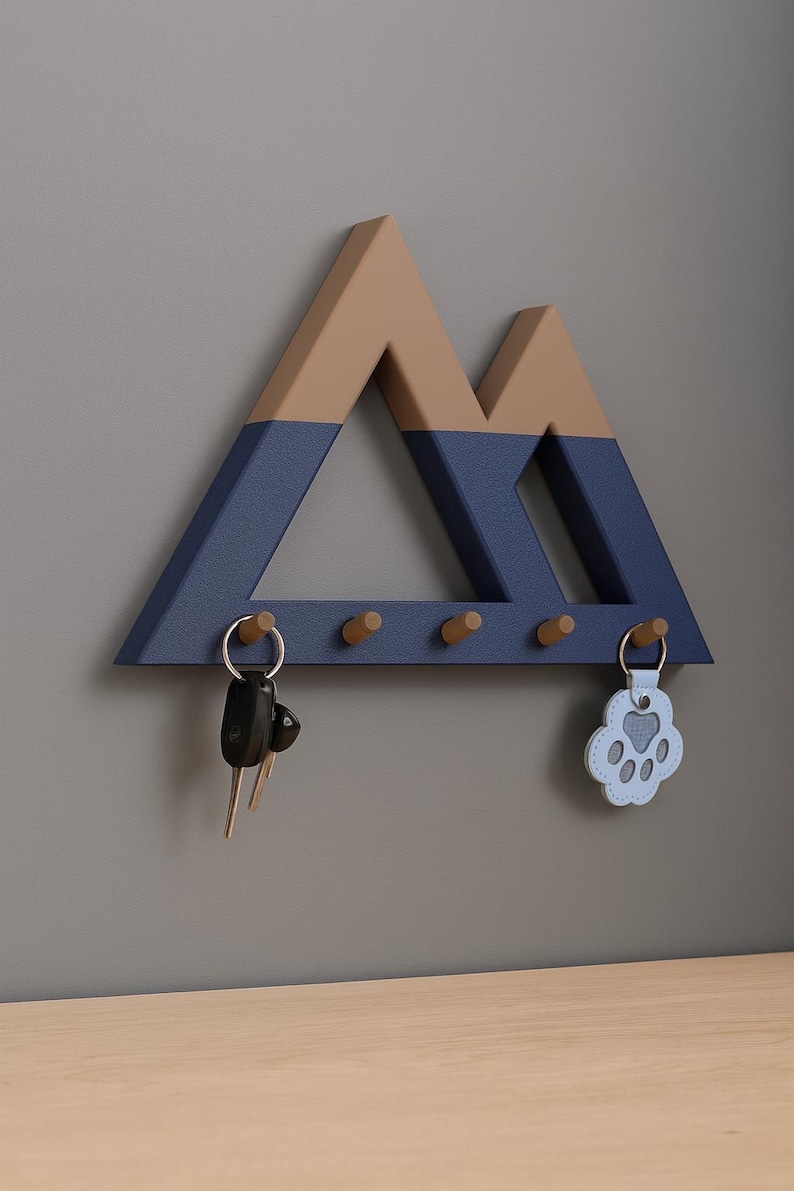 Blue and brown Mountain key holder on a gray wall holding car keys and a light blue paw-print key tag on its end pegs