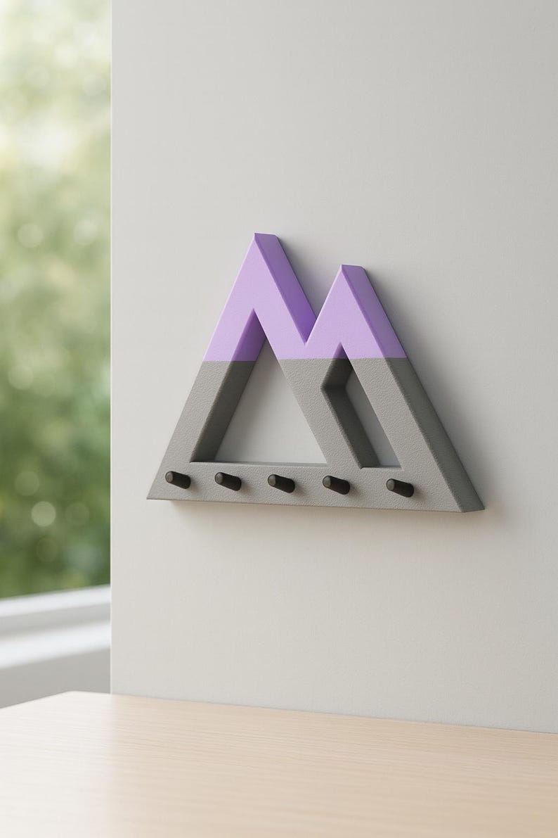 Gray Mountain key holder with lavender peaks on a pale wall above a light wood surface, a green window view at left