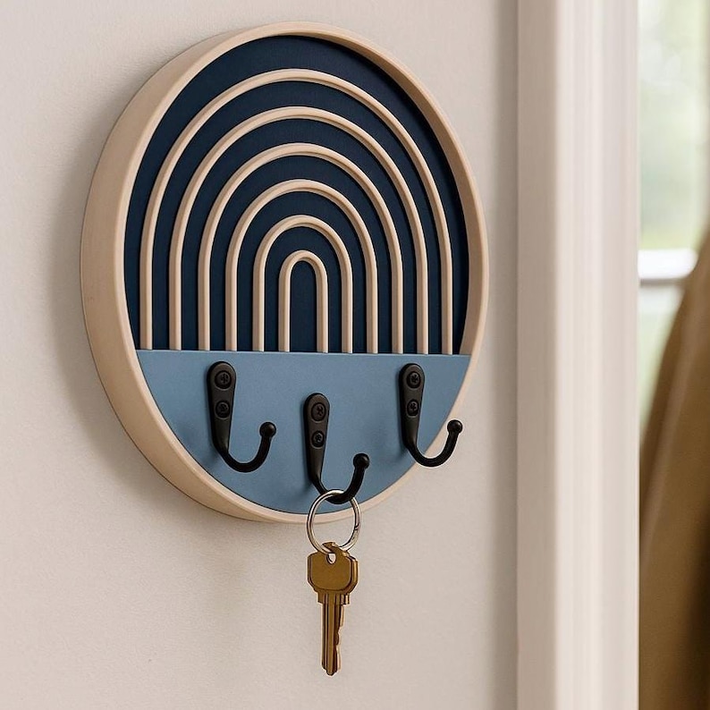 Dark blue Boho key holder in a tight close-up, showing its raised beige arches, deep rim and a brass key on the middle hook