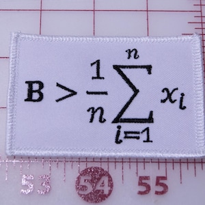 May include: White rectangular patch with black embroidered mathematical formula: B > (1/n)∑xi. The patch has a white border and is placed on a grid with inch markings.