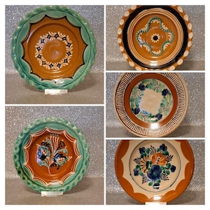 May include: A selection of five decorative ceramic plates. Each plate has a brown centre and a variety of colours including green, blue, and white. The plates have scalloped edges and floral or geometric patterns. Measurements are in centimetres.