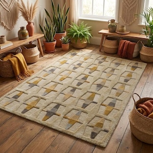 May include: A rectangular area rug featuring a repeating geometric pattern of interconnected shapes in shades of cream, mustard yellow, and slate grey. The rug has a textured, tufted pile surface and is laid flat on a wooden floor surface.