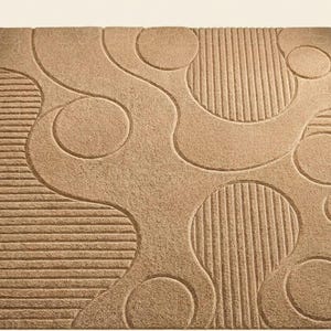 May include: A rectangular area rug in a solid tan color featuring a textured surface with a pattern of raised circular shapes and sections of parallel horizontal lines that create a tactile contrast across the entire piece of home decor.